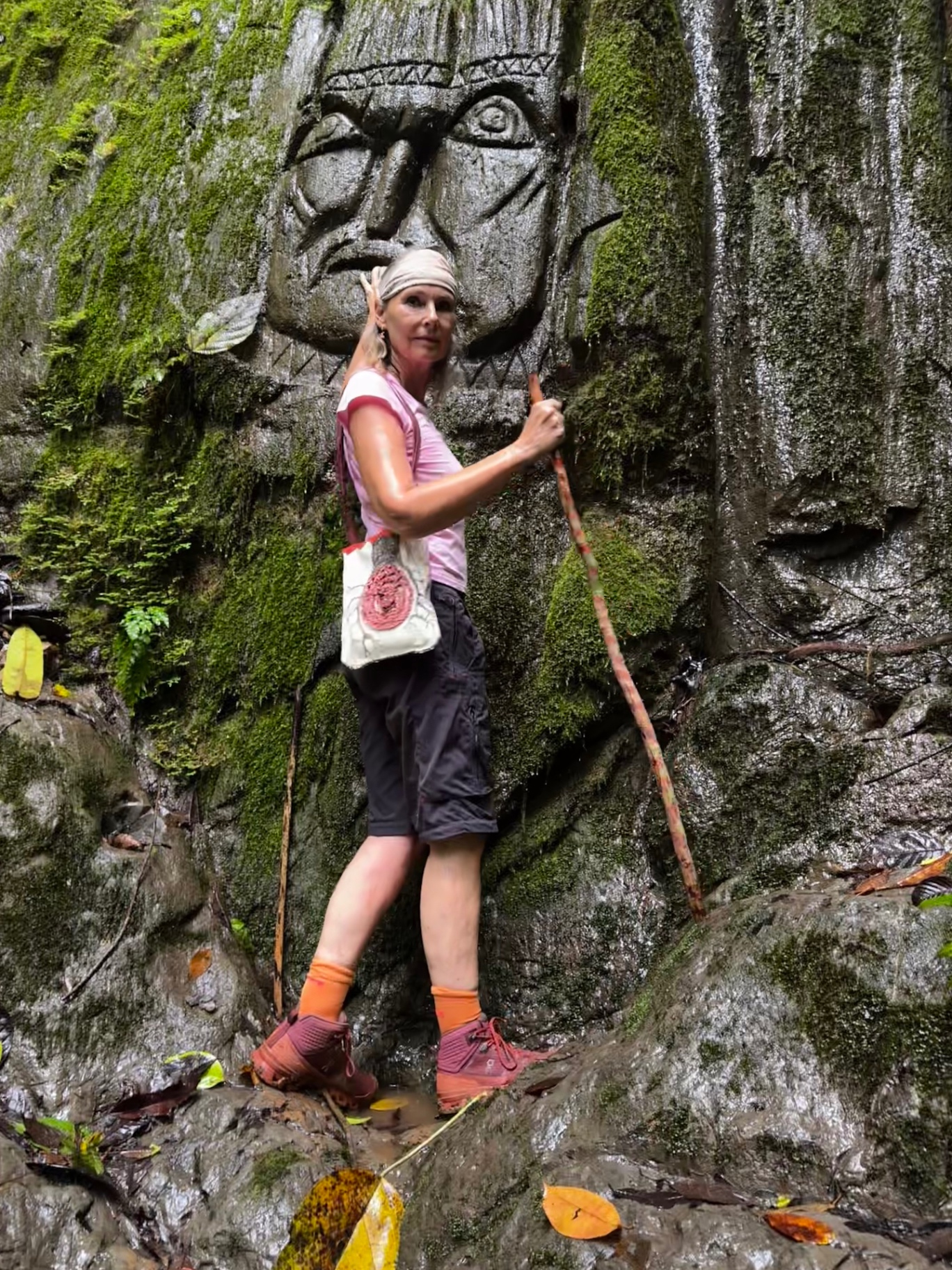 Kathrin beside an ancient stone face carved into a moss-covered cliff in the Diquís rainforest.
