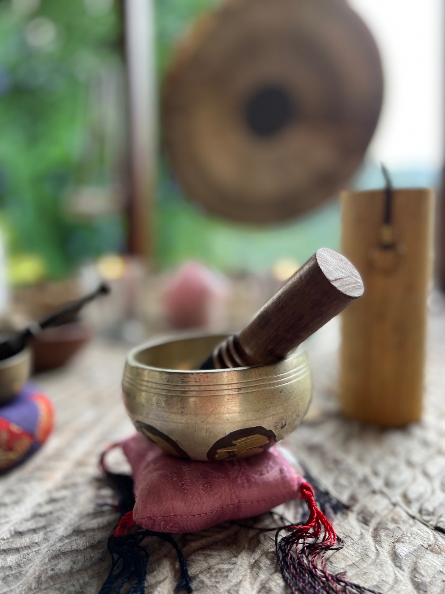 Tibetan singing bowl resting on a silk cushion before a gong