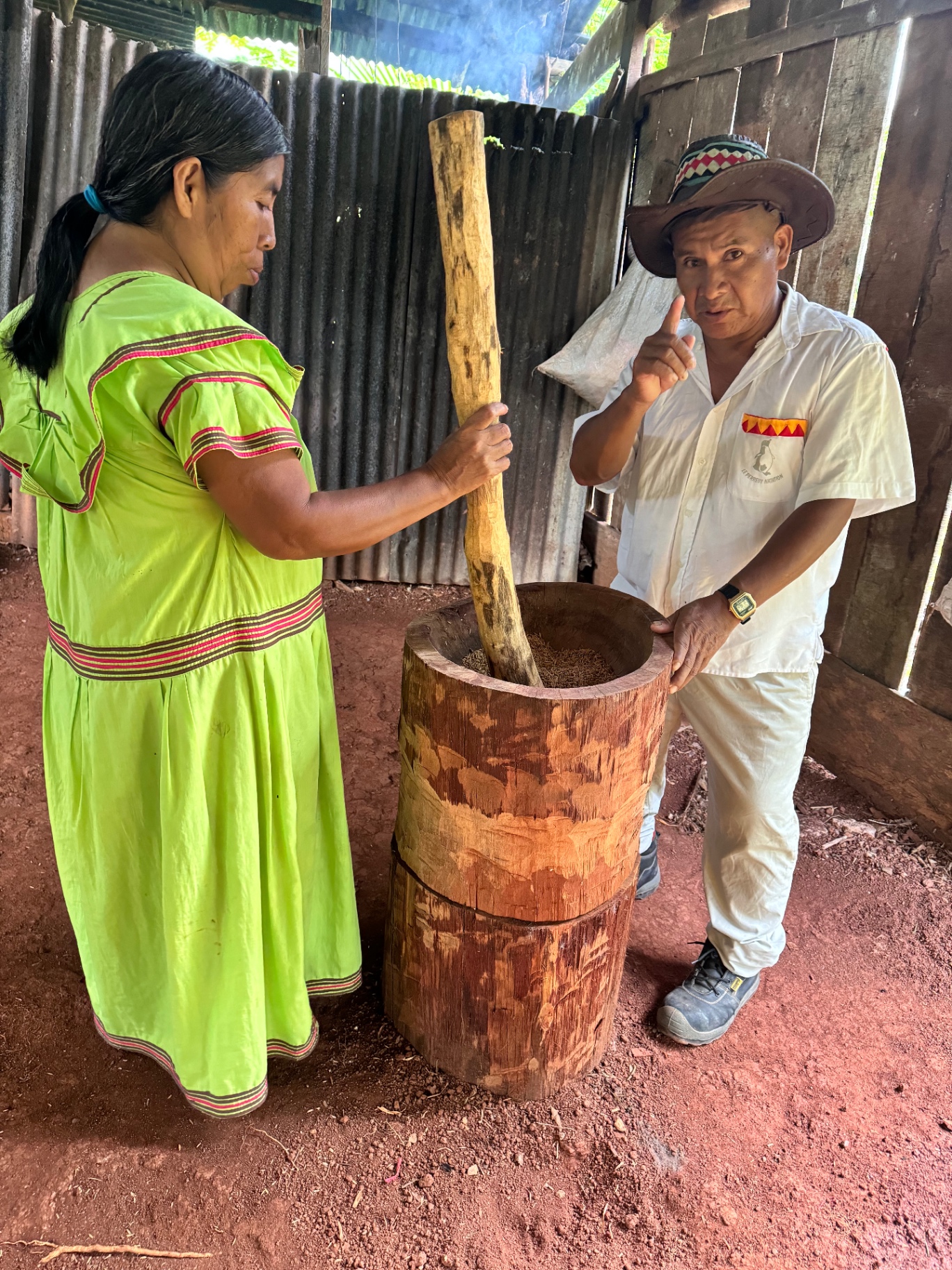 A Ngäbe-Buglé wisdom-keeper teaching the preparation of sacred grain in a wooden mortar.