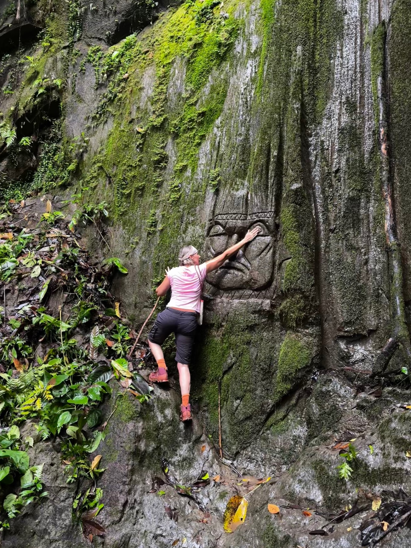 Communion with a stone guardian — palm to carved face in the cathedral of the forest.
